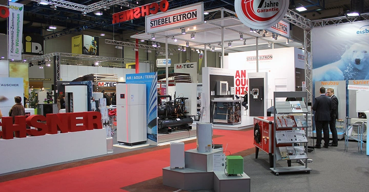 Galerie-Bild 11: Stand mit verschiedenen Heizungs- und Klimageräten ausgestellt Auf dem Schild steht Stiebel Eltron im Hintergrund sind Messebesucher zu sehen Der Stand befindet sich in einer großen Messehalle