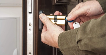 Hand hält ein neues Türschloss kontext Wohnungstür Vorbereitung zum Einbau in eine Tür helle Innenansicht.