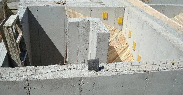 Galerie-Bild 14: Unvollständiges Betonfundament stehen still auf einer Baustelle mit Holzbrettern und gelben Bauelementen im inneren Bereich umgeben von Erde.