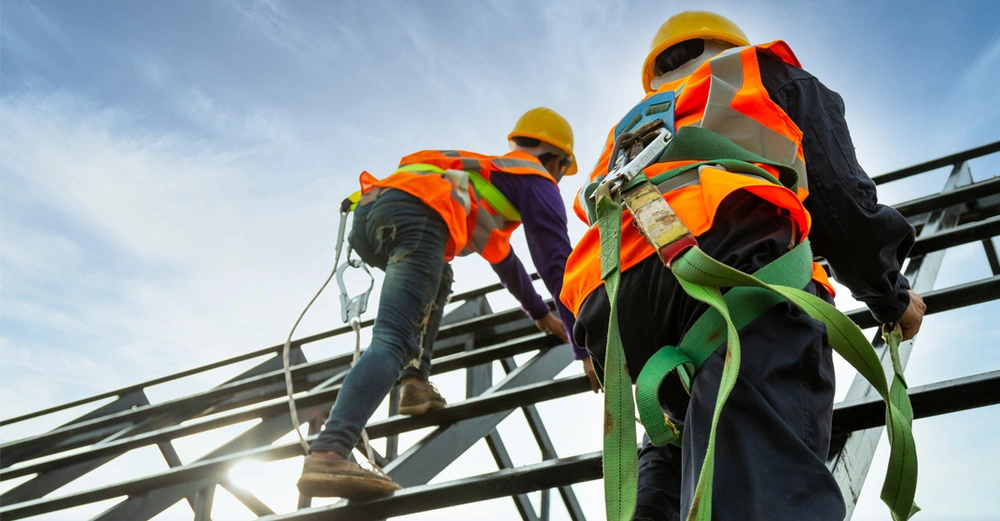 Froschperspektive von zwei Bauarbeitern, die auf ein Metallgerüst klettern.