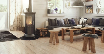 modernes, helles Wohnzimmer, dunkle Couch im Hintergrund, heller Holzboden, massiver HolzCouchtisch, links im Bild moderner Kaminofen vor Fensterfront