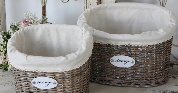 Galerie-Bild 10: Zwei geflochtene Körbe mit Leinenfutter stehen auf einem Holztisch in einer dekorativen Umgebung. Auf beiden Körben befindet sich ein Schild mit der Aufschrift storage.