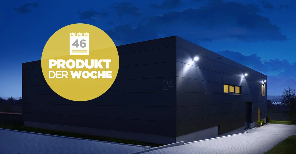 Ein rechteckiges, modernes Gebäude leuchtet nachts im Freien, umgeben von einem Pflasterweg und Bäumen. Ein gelber Kreis mit Text rechts oben zeigt 46 PRODUKT DER WOCHE.