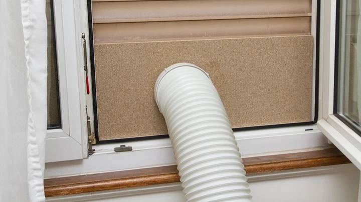 Eine DIY-Fensterabdichtung für eine mobile Klimaanlage: Schneiden Sie eine Platte zu und bohren Sie ein Loch für den Schlauch. Achtung: Die Kanten müssen gut isoliert werden!