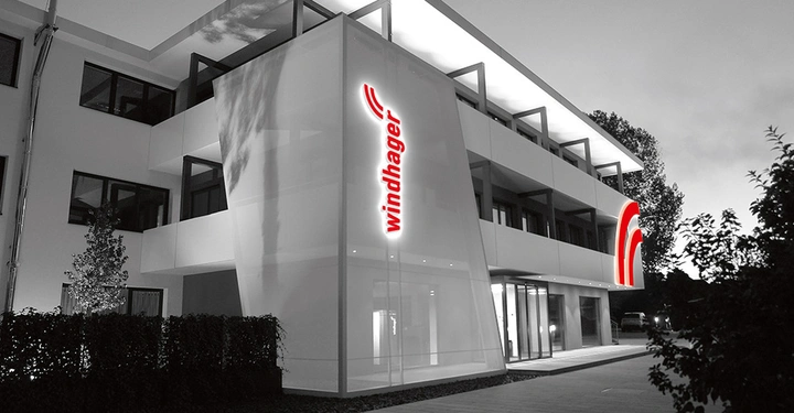 Modernes, mehrstöckiges Gebäude von Windhager in Schwarz-Weiß mit leuchtend roter Windhager-Beschilderung an der Fassade.