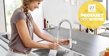 Eine Frau füllt ein Glas mit Wasser am Wasserhahn in einer modernen Küche. Im Hintergrund Text: 27 PRODUKT DER WOCHE