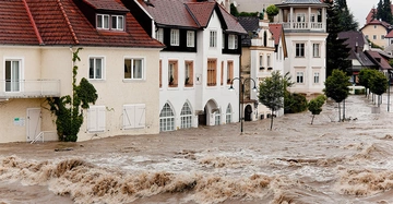 Hochwasserkatastrophe in historischer Altstadt. Erdgeschoß fast komplett unter Wasser. Reißende, braune Fluten wälzen sich durch die Straßen.