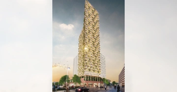 Ein hohes modernes Gebäude beleuchtet die Umgebung in einer urbanen Straße mit Menschen und fahrenden Autos bei Sonnenuntergang. Im Hintergrund sind mehrstöckige Bauwerke zu sehen.