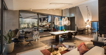 Wohnzimmer mit modernen Möbeln und stilvollen Beleuchtungselementen offene Sitzecke mit Sofas und Sesseln Esstisch mit Hängelampen große Fensterfront mit Blick auf Innenhof dunkler Holzboden helle Wände