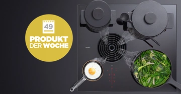 Zwei Töpfe und zwei Pfannen kochen auf einem modernen Kochfeld mit Dunstabzug. In einer Pfanne brät ein Spiegelei und in der anderen kochen grüne Gemüsesorten. Gelber Kreis mit Text: 49 PRODUKT DER WOCHE.