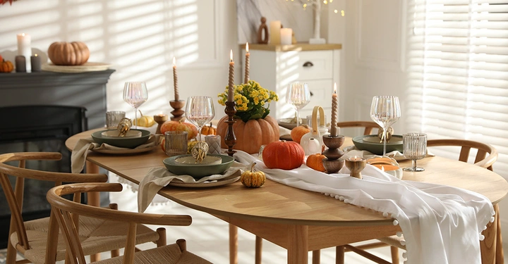 Stylischer gedeckter Esstisch mit Kürbissen und Kerzen. Herbstliche Dekoration für das Esszimer.