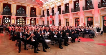 Menschen sitzen im Publikum in großem schönem Saal