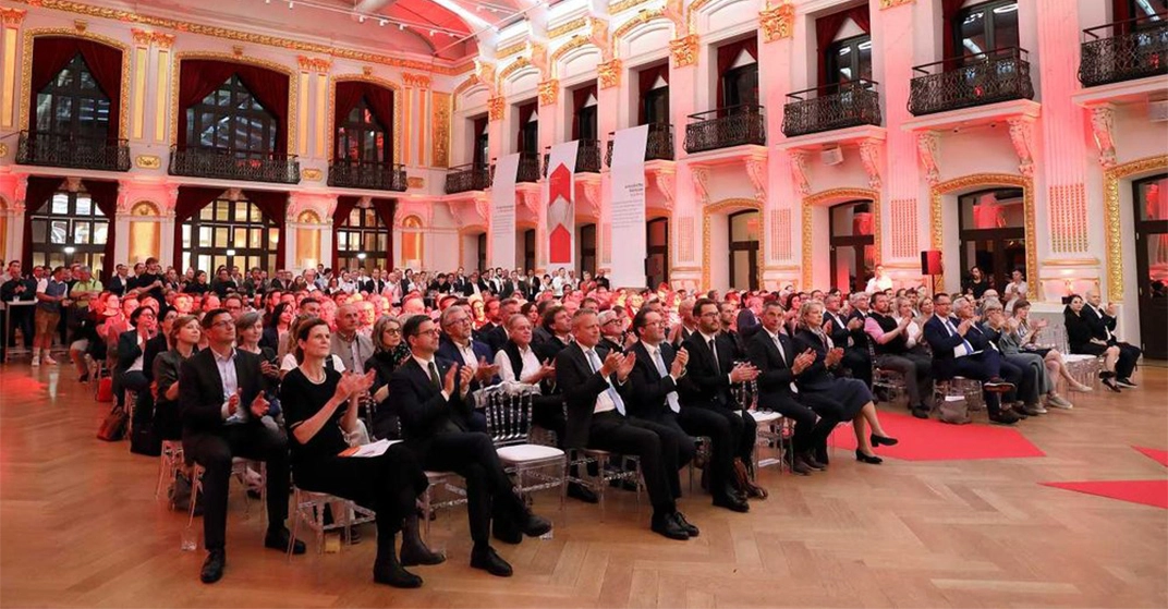 Menschen sitzen im Publikum in großem schönem Saal