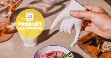 Eine Hand hält eine keramische Handform in einer Küchenumgebung neben einer Schüssel mit rosa Dipzubereitung. Links daneben steht eine Glaskanne. Text im Bild: 23 Produkt der Woche.