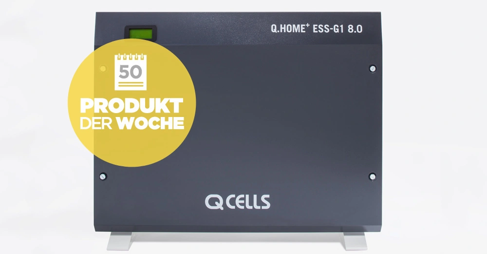 Schwarzer rechteckiger Energie-Wandspeicher mit Q CELLS-Logo steht auf hellgrauem Hintergrund. Text auf der Vorderseite Q.HOME+ ESS-G1 8.0 und gelber Kreis mit Produkt der Woche 50.