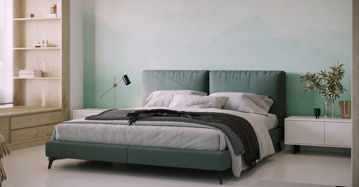 Ein grünes Bett steht in einem modern eingerichteten Schlafzimmer vor einer pastellgrünen Wand umgeben von Nachttischen Lampen und einer eingebauten Holzbücherschrank links und Pflanzen rechts.