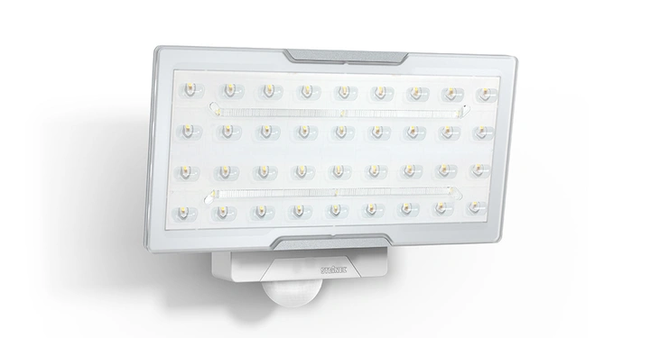 Rechteckiger LED-Strahler mit 36 leuchtenden Dioden an einer weißen Wand befestigt unten befindet sich ein Bewegungssensor. Texte: STEINEL