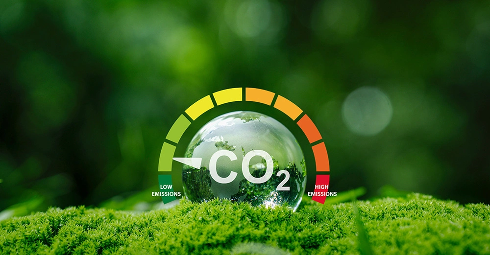 Eine Kristallkugel auf grünem Moos, die eine CO2-Emissionsanzeige im grünen Bereich für 'niedrige Emissionen' zeigt. Symbol für die neue Zertifizierung des CO2-Fußabdrucks für Produkte (Product Carbon Footprint) nach ISO 14067 durch Quality Austria.