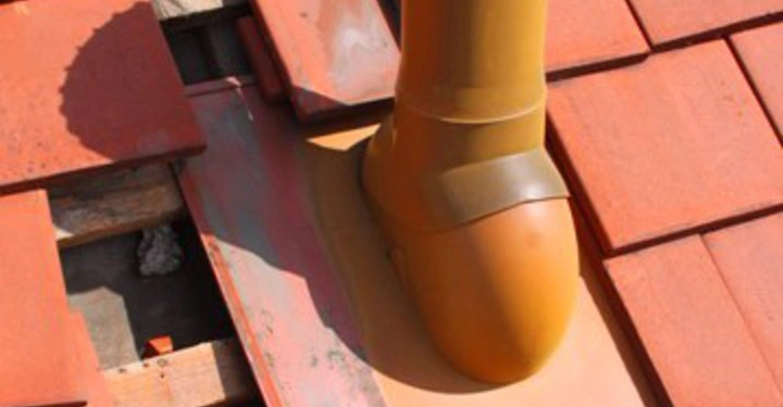 Galerie-Bild 33: Ein gelbes Lüftungsrohr verläuft über rote Dachziegel auf einem Hausdach.