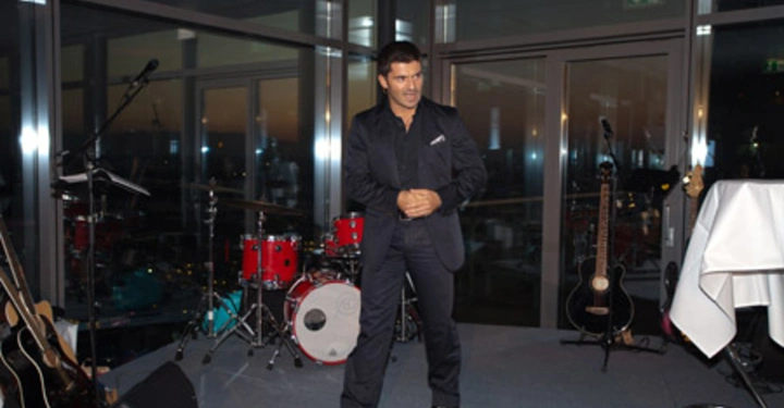 Galerie-Bild 63: Ein Mann steht auf einer Bühne Er scheint zu sprechen oder zu singen Im Hintergrund sind Musikinstrumente wie ein Schlagzeug und Gitarren in einem modernen Raum zu sehen