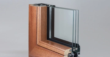 Holzrahmenfenster mit dreifach verglasten Scheiben steht in einem isolierten, neutralen Studiohintergrund.