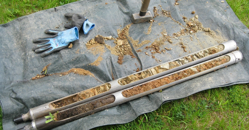 Mit Erde befüllte Bodenprobesonde nach Erdbohrung auf einem Grundstück