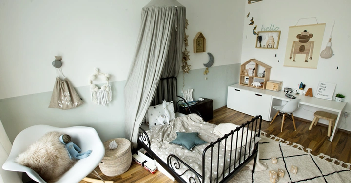 Galerie-Bild 1: Schwarzes Kinderbett mit grauem Baldachin steht in einem liebevoll dekorierten Zimmer mit weißen und holzfarbenen Möbeln Wandkunst und Spielsachen Ein Buch trägt den Titel The Book with No Pictures