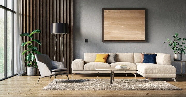 Großes beige Sofa mit bunten Kissen steht vor einer grauen Wand mit Holzbilderrahmen Glastür und Pflanzen links Beistelltisch und Teppich in modernem Wohnzimmer.