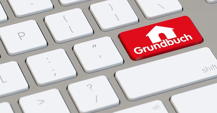Eine QWERTZ-Tastatur enthält eine rote Taste mit dem Symbol eines Hauses und dem Text Grundbuch in einem modernen Computerumfeld